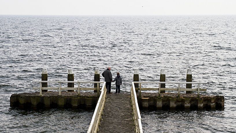 Großvater und Enkel schauen auf den See. von Ron Van Rutten