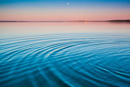 The turquoise lake at dawn.small symmetrical waves of blue and turquoise lake surface at dawn, red a