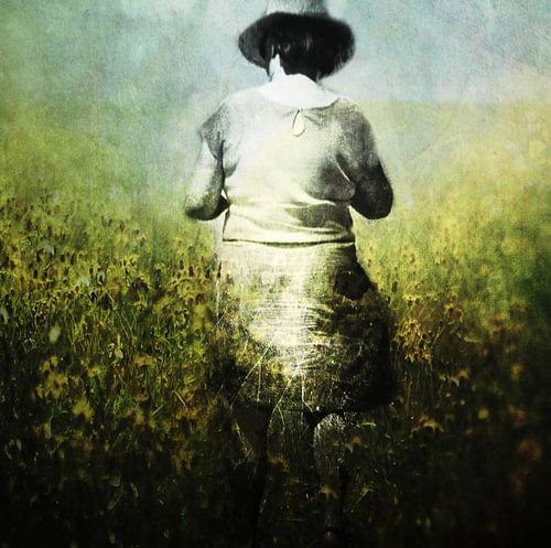 Frau mit Hut geht in einem gelben Blumenfeld