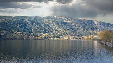 Herfstmeer met weerspiegeling en kleurrijk bos onder blauwe hemel