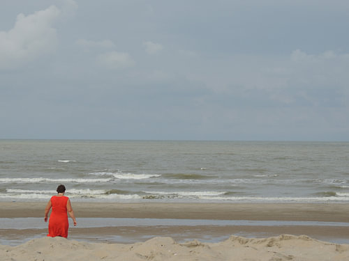 vrouw in rood aan zee