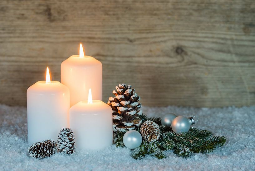 Festive burning Advent and Christmas candles with traditional decoration on snow by Alex Winter