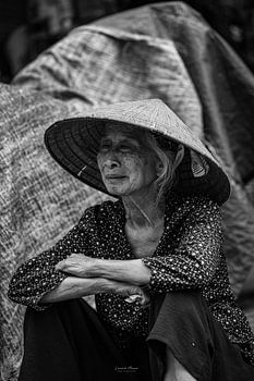 Femme âgée vietnamienne assise portant un chapeau