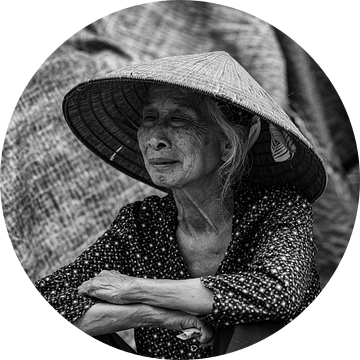 Zittende vietnamese oudere vrouw met hoed op