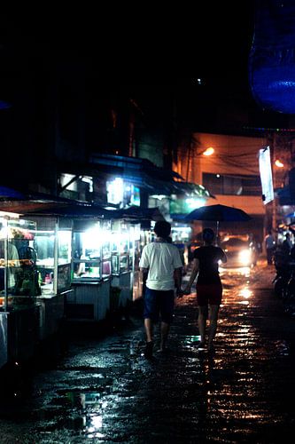 Verliefd koppeltje op regenachtige Aziatische nachtmarkt