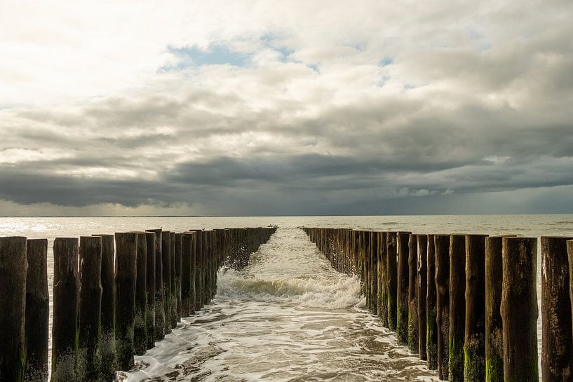 Zee met golfbrekers en aanstormend water. van Helene van Rijn