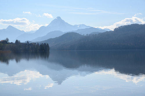 Weissensee, idyllischer See im staubigen Morgenlicht vor den blauen Bergen der bayerischen Alpen bei