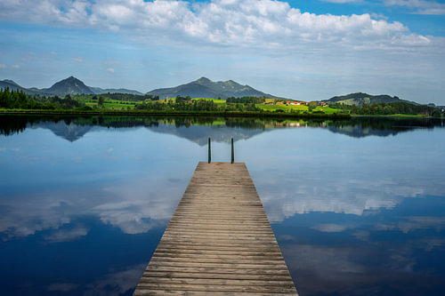 Holzsteg am Hopfensee unter weitem Wolkenhimmel