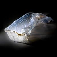 empty plastic packaging for food shown like an art sculpture against a black background, waste of th