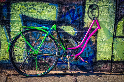 Neon auf Asphalt – Fahrradfragment vor Graffiti