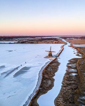 Skater bei einer Mühle im winterlichen friesischen Polder von Ewold Kooistra