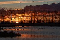 Zonsondergang met grote donkere wolken, en reflecties in het water