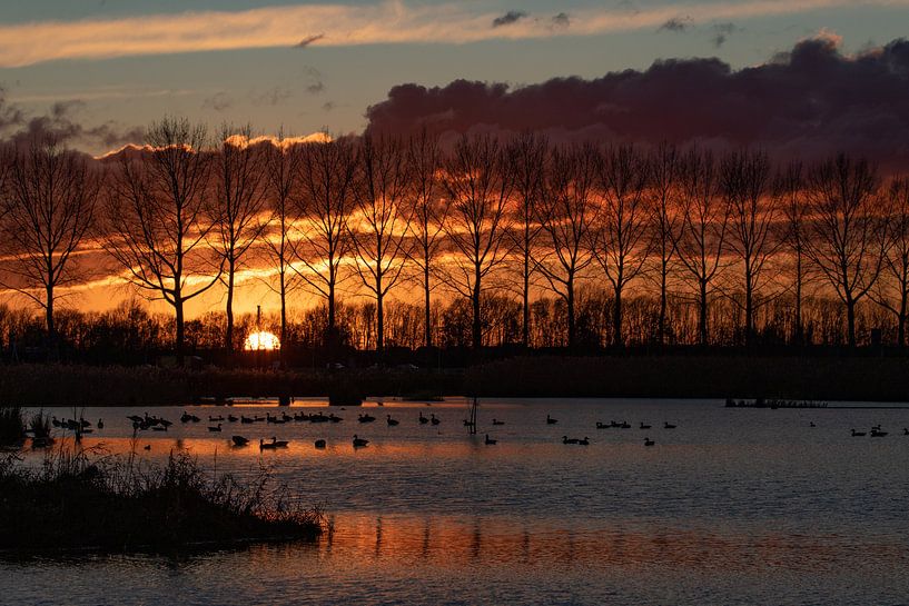 Sunset with large dark clouds and reflections in the water by Anne Ponsen