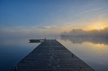 Blick über das Wasser mit Steg und Sonnenaufgang