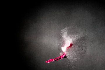 Opname met hoge snelheid van roze ballondelen en wegspattende waterdruppels na geweerschot voor donk van pixxelmixx