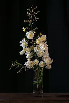 Vintage rose branch with yellow white flowers in a glass vase ag