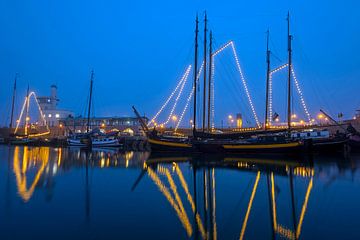 Versierde traditionele boten in de haven van Harlingen bij zonsondergang in Nederland van Eye on You