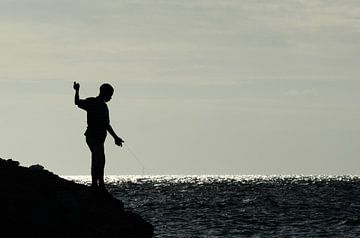 Jongen op rotsen aan het vissen