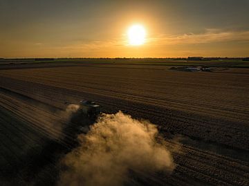 Combine oogst tarwe tijdens zomerse zonsondergang van Sjoerd van der Wal
