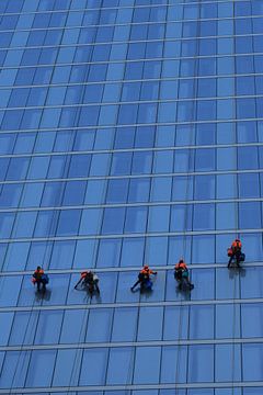 Vijf hardwerkende glazenwassers aan het werk op een blauw modern hoog gebouw van Studio LE-gals