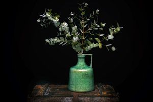 Grüner Krug mit Eukalyptus auf einer alten Truhe