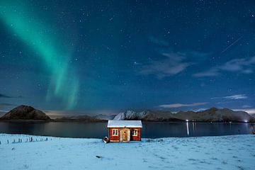 Rode hut in de sneeuw en aurora borealis