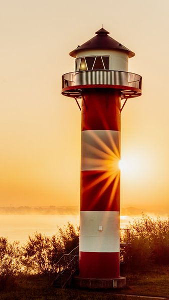 Leuchtturm am Morgen mit Sonnenstern von Berthold Ambros