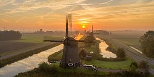Typical Dutch windmill during sunrise sur Menno Schaefer