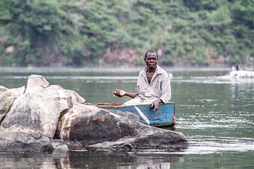 Visser rookt een sigaretje op de rivier de Nijl In Uganda