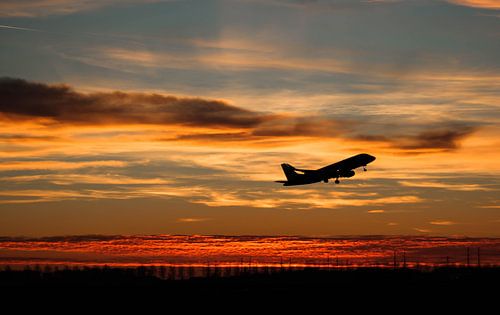 KLM Embraer vertrekt tijdens zonsondergang vanaf Schiphol