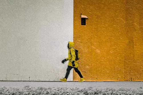 Symmetrische straatfoto van wandelende man in sneeuwstorm en levendige kleuren