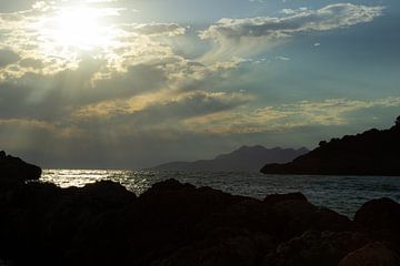 Die Sonne brennt über dem Meer mit Felsen im Vordergrund. von Edith Keijzer