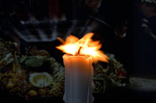 Brandende kaars met bewegende vlam tegen een donkere achtergrond