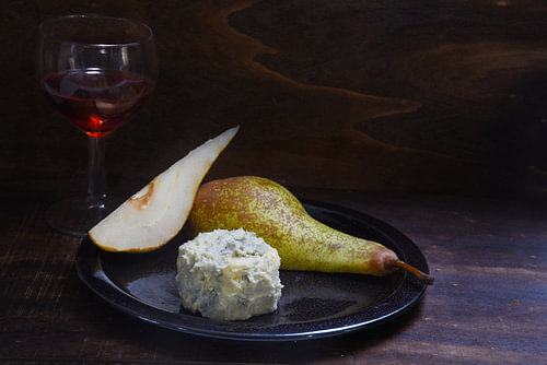 Stelzenkäse, Birnen und roter Portwein auf einem dunklen, rustikalen Holzuntergrund, Kopierraum, aus
