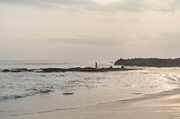 Man on rock in water with sunset