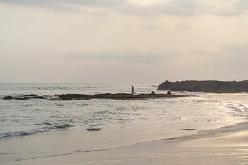 Mann auf Felsen im Wasser mit Sonnenuntergang