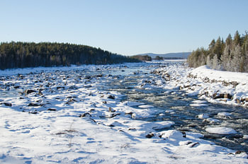 Fließendes Wasser durch das verschneite schwedische Lappland