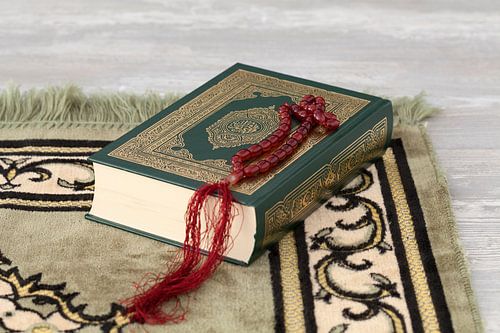 Koranbuch und Gebetsperlen auf einem Gebetsteppich