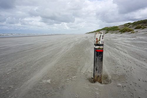 Verweerde strandpaal met verlaten strand