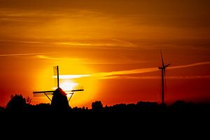 Een oude en nieuwe windmolen met een zonsondergang van Jan Hermsen