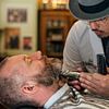 Ein Barbier trimmt den Bart eines Mannes von Bob Janssen