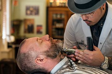 Ein Barbier trimmt den Bart eines Mannes von Bob Janssen