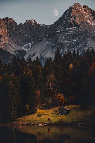 Alpen-Idylle im Mondschein. Berghütte am See bei Nacht
