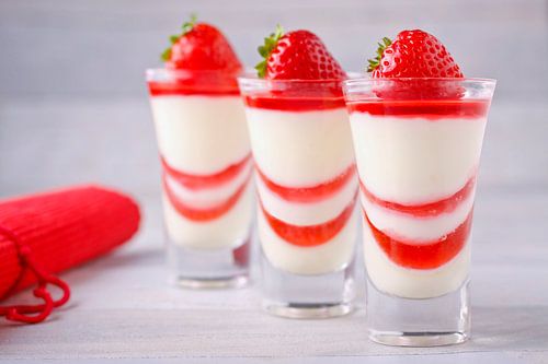 3 dessertglaasjes met pannacotta en aardbeiengelei.