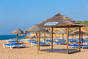 Rieten parasols en strandbedden op het strand aan de kust in Albufeira in Portugal