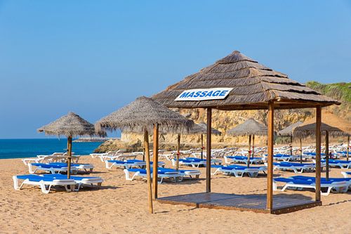 Wicker umbrellas and beach beds on the beach of the coast in Albufeira in Portugal
