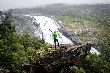 Adventure at Nyastølfossen: Hiker on a Rock in front of the Majestic Waterfall