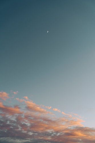 Opkomende maan bij zonsondergang boven zachte wolken