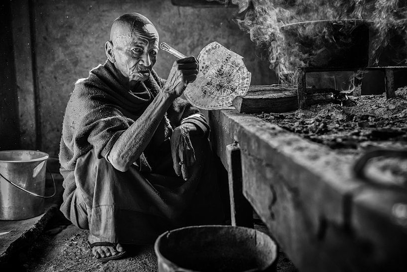 Un moine fait la cuisine dans une pièce plutôt obscure d'un monastère près d'Inle au Myanmar. par Wout Kok