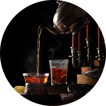 Het gieten van hete dampende thee uit een vintage theepot in glazen kopjes op een rustieke tafel met van Maren Winter